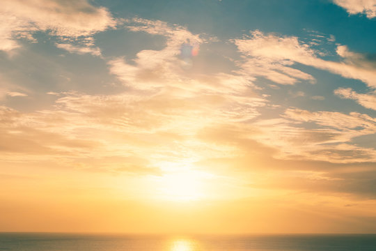 Good morning sunrise or sunset sky background with cloud and early sun rising over ocean sea horizon with reflective wavy water skyline for early bird, beginning new day or holiday vacation