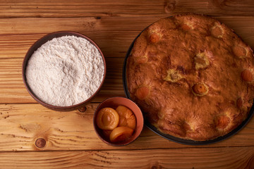 Fototapeta na wymiar apricot pie and a bowl with flour and other ingredients and tools table