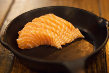 Raw salmon sashimi meat on black dish and wood table . Japanese healthy fresh food .