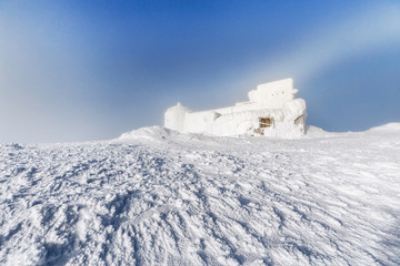 Fantastic sunny winter landscape, snowstorm background. Observatory covered with snow in mountains.