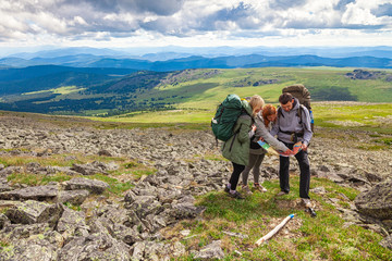 A team of travelers from two women and men with backpacks orient themselves to the terrain, study...