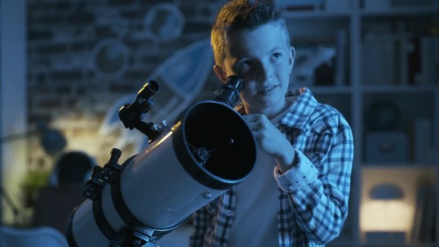 Cute boy looking at the stars through a telescope at night