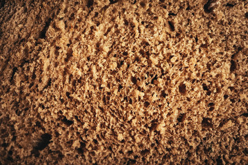 A piece of handmade freshly baked rye bread, texture background, closeup.