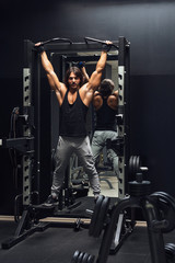 Fototapeta na wymiar Athletic muscular man doing pull-ups in a gym