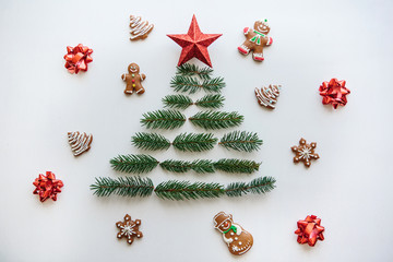 Creative idea for Christmas or New Year theme. A Christmas tree from spruce branches and a star on top. Nearby lie gingerbread cookies. Celebratory concept.