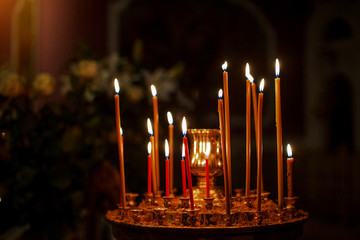 Many church candles burn in cathedral, in dark