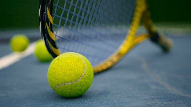 Close up of tennis equipment on the court. Sport, recreation concept. Yellow racket with a tennis ball in motion on a clay green blue court next to the white line with copy space and soft focus.