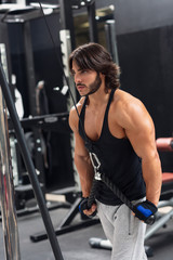 Fototapeta na wymiar Young man exercising triceps pulldown at the gym