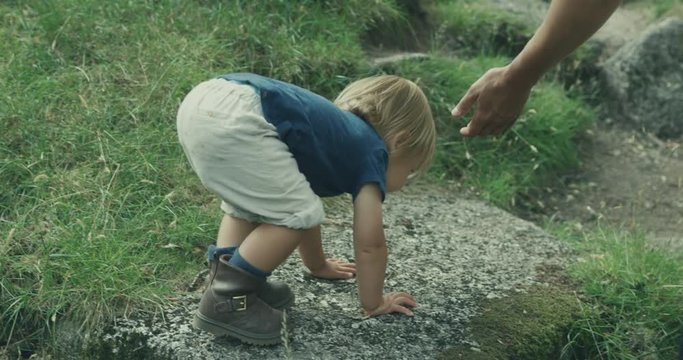 Little toddler walking in nature with his mother and other family members