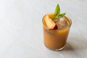 Peach Bourbon Cocktail with Peach Slice, Mint Leaves and Ice.