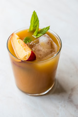 Peach Bourbon Cocktail with Peach Slice, Mint Leaves and Ice.