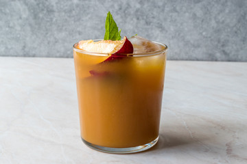 Peach Bourbon Cocktail with Peach Slice, Mint Leaves and Ice.