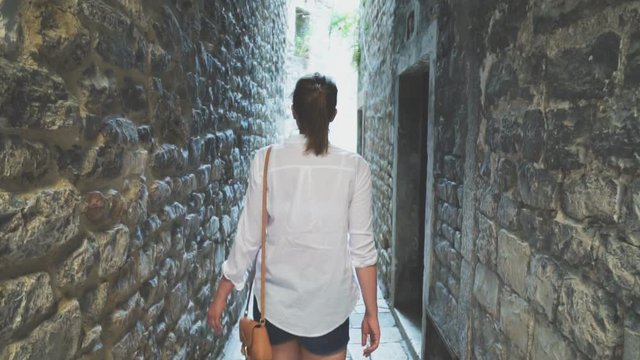 Female tourist is walking along the old narrow streets of the city.