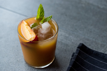Peach Bourbon Cocktail with Peach Slice, Mint Leaves and Ice.