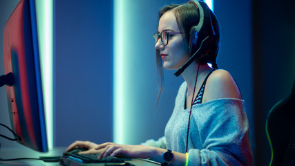 Beautiful Professional Gamer Girl Playing in First-Person Shooter Online Video Game on Her Personal...