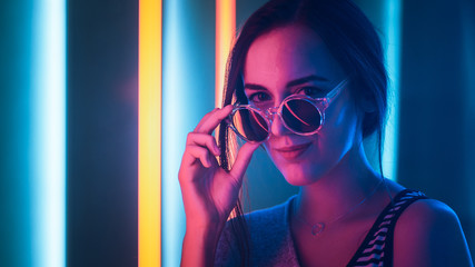 Portrait Shot of a Young Elegant Disco Girl Wearing Sunglasses. Room Lit in Retro / Retrowave Style...