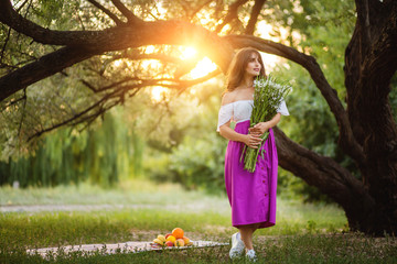 Girl with an armful of wildflowers on a sunset background
