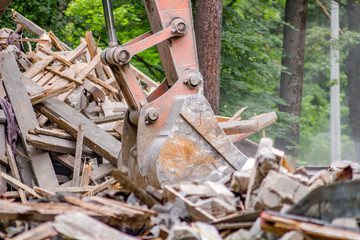 Excavator bucket loads construction debris after the demolition of the old building
