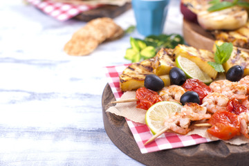 Picnic with grilled food. Shrimp and grilled vegetables with lime and olives. Delicious summer lunch and plastic dishes. Top view