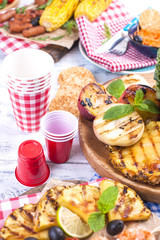 Picnic with grilled food. Different vegetables and fruits on barbecue and seafood, shrimp. Delicious summer lunch. Top view. Copy space,