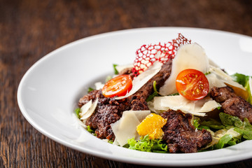 Salad from the mix of lettuce, lettuce and iceberg leaves, with cherry tomatoes, orange and grilled beef on the grill. beautiful serve in the restaurant. Copy space, selective focus