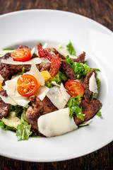 Salad from the mix of lettuce, lettuce and iceberg leaves, with cherry tomatoes, orange and grilled beef on the grill. beautiful serve in the restaurant. Copy space, selective focus