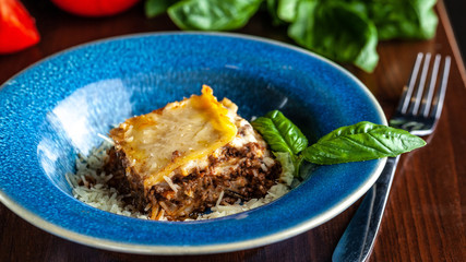Italian lasagna with minced meat bolognese, carrots, and Parmesan cheese in a beautiful ceramic blue plate. Copy space, selective focus