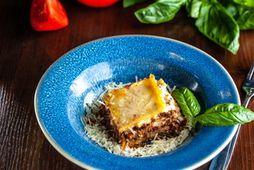 Italian lasagna with minced meat bolognese, carrots, and Parmesan cheese in a beautiful ceramic blue plate. Copy space, selective focus