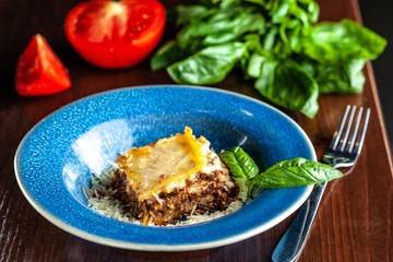 Italian lasagna with minced meat bolognese, carrots, and Parmesan cheese in a beautiful ceramic blue plate. Copy space, selective focus