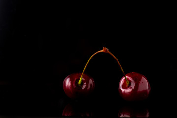 Two ripe cherries on black reflecting background
