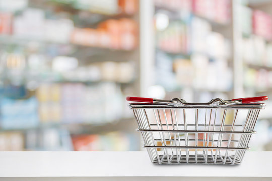 Empty Shopping Basket On Pharmacy Drugstore Counter With Blur Shelves Of Medicine And Vitamin Supplements Background