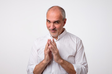 Cunning tricky mature man thinking looking in side with hand together over white background....