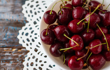 Fresh cherry berries in white bowl on rustic wooden table and vintage background. top view,close up