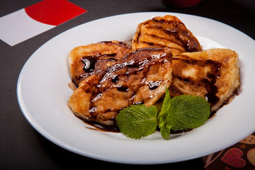 Pancakes with jam decorated with a mint leaf on a white plate on a black background. Photo in the studio