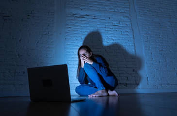 Sad and scared female Young woman with computer laptop suffering cyberbullying and harassment being...