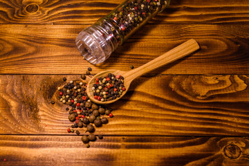 Pepper mill and scattered spices on the wooden table. Top view