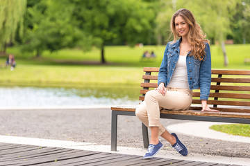 Young woman sitting on bench in park - Powered by Adobe