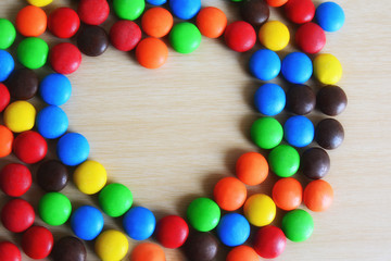 heart made of colored button-shaped chocolates on isolate,white background.
