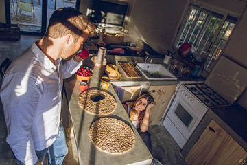 A couple in the kitchen at home drinking tea and looking at each other