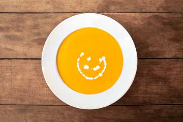  Squash Soup. Fresh homemade cream of Carrot and Pumpkin  soup with a swirl of cream  on dark wooden table. Top view