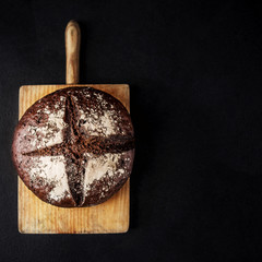 Fresh bread on black concrete background. Top view with copy space. Rye Bread on cutting board closeup.