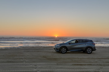 Fototapeta na wymiar grey car on the sand beach at sunset Oceano Dunes SVRA, San Luis Obispo county, California, USA