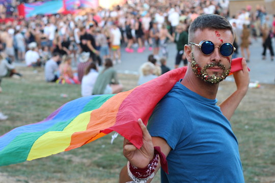 Man with glitter beard holding rainbow flag
