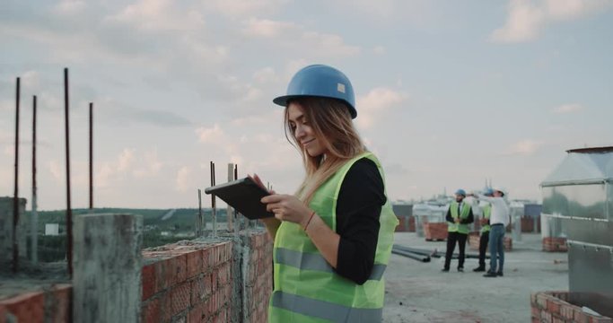 Woman expert engineer and group of builders analyzing the construction plan of building using tablet