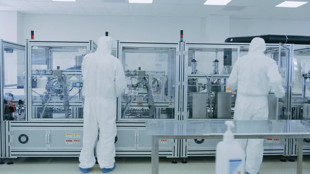 Manufacturing Laboratory where Scientists in Protective Coverall's Work with Industrial High Precision 3D Printing Machinery. Manufacturing Pharmaceutical / Technological / Industrial Products.