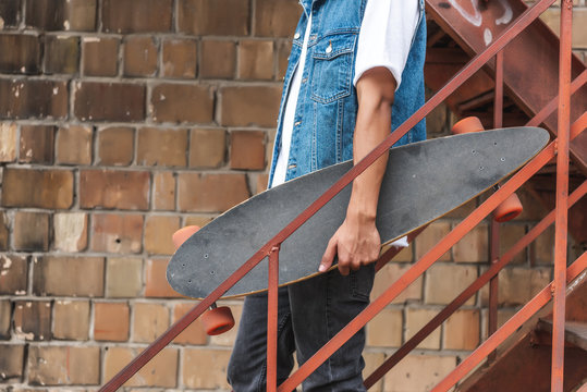 cropped image of stylish man holding skateboard at urban street