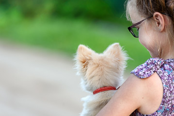 A girl with a little dog on her shoulder, rear view