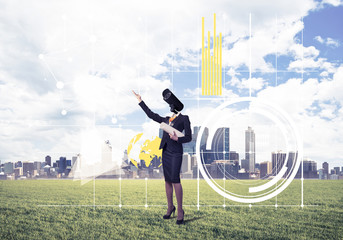 Camera headed woman standing on green grass against modern citys