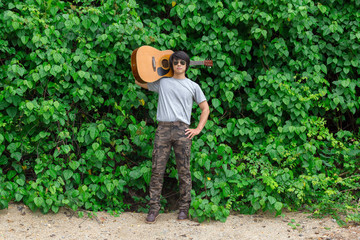 The guy is holding the guitar, outdoo, cargo pants