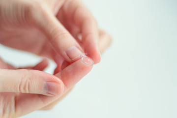 Close up contact lens on the tip of woman's finger